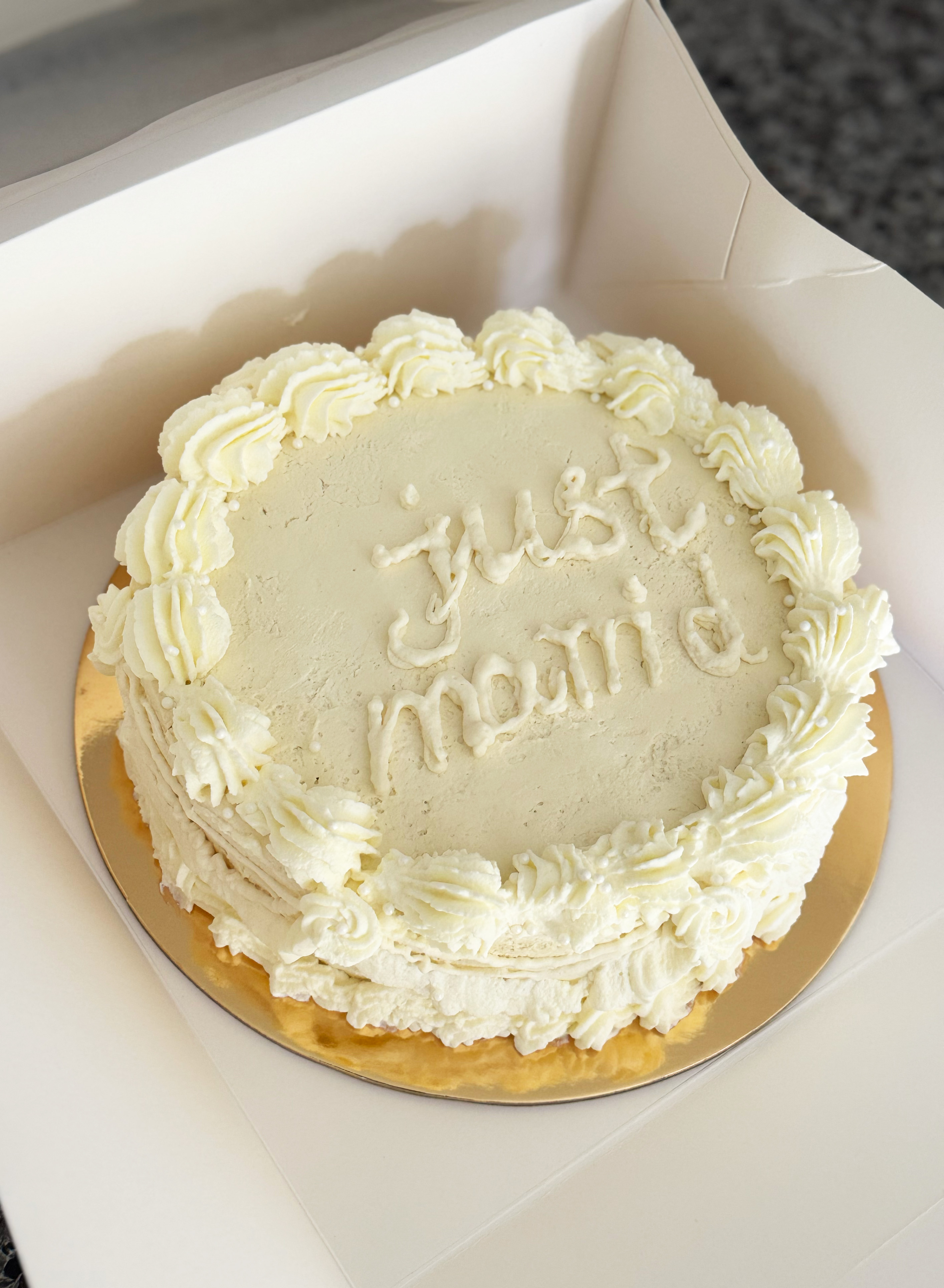 White frosted cake with 'just mama' written on top